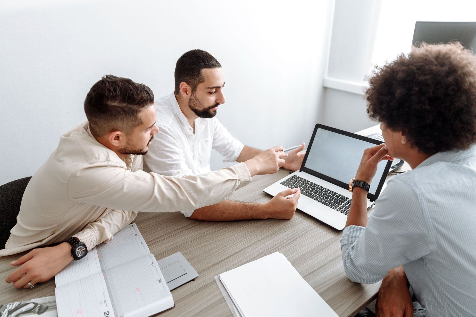 Three people plan a new business together over a laptop and a planner.