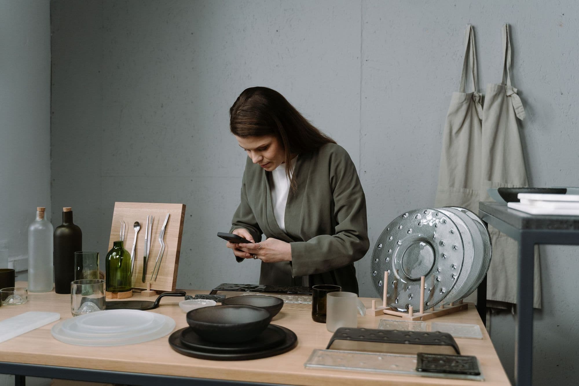 A shop owner photographs her tableware range with her phone for social media.